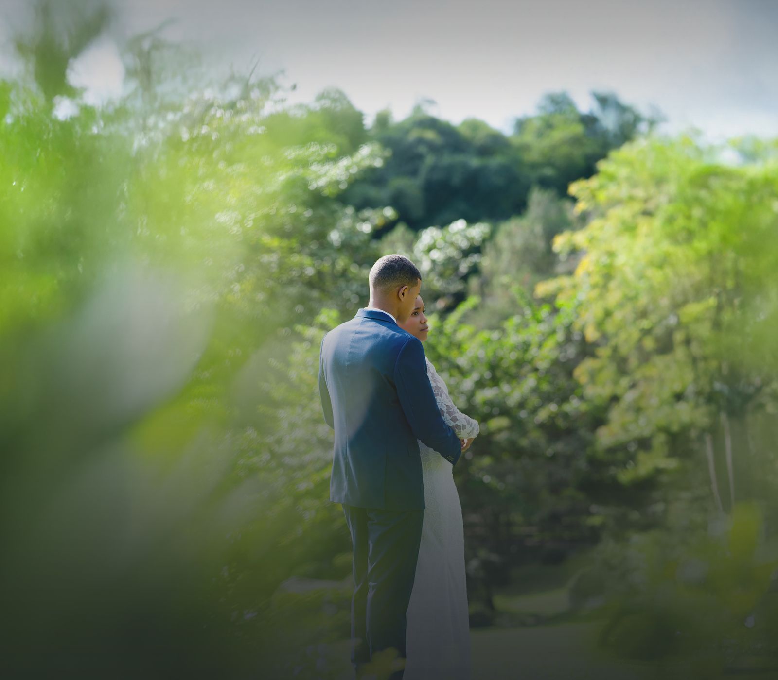 Novios abrazados entre la vegetación